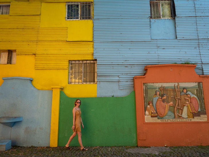 A girl walks in front of colourful walls at El Caminito, Buenos Aires, Argentina