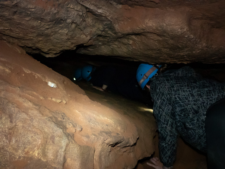 People crawl through tight spaces in a dark cave, Umajalanta, Bolivia