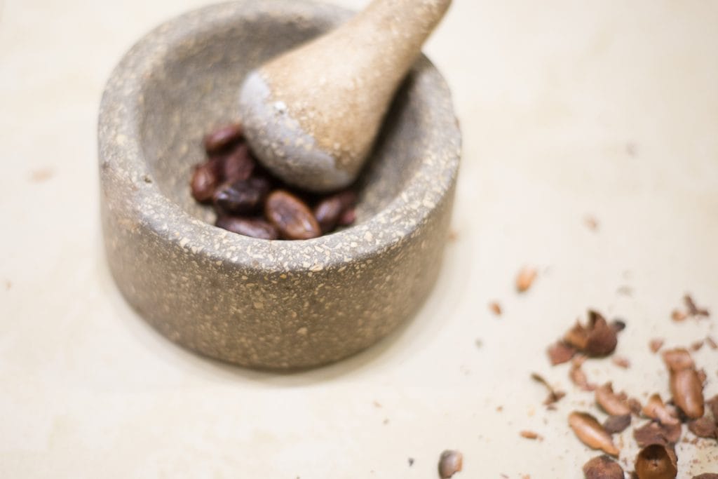 Cusco's chocolate museum - A mortar and pestle crushing cocoa nibs on a bench with cacao shells on the side