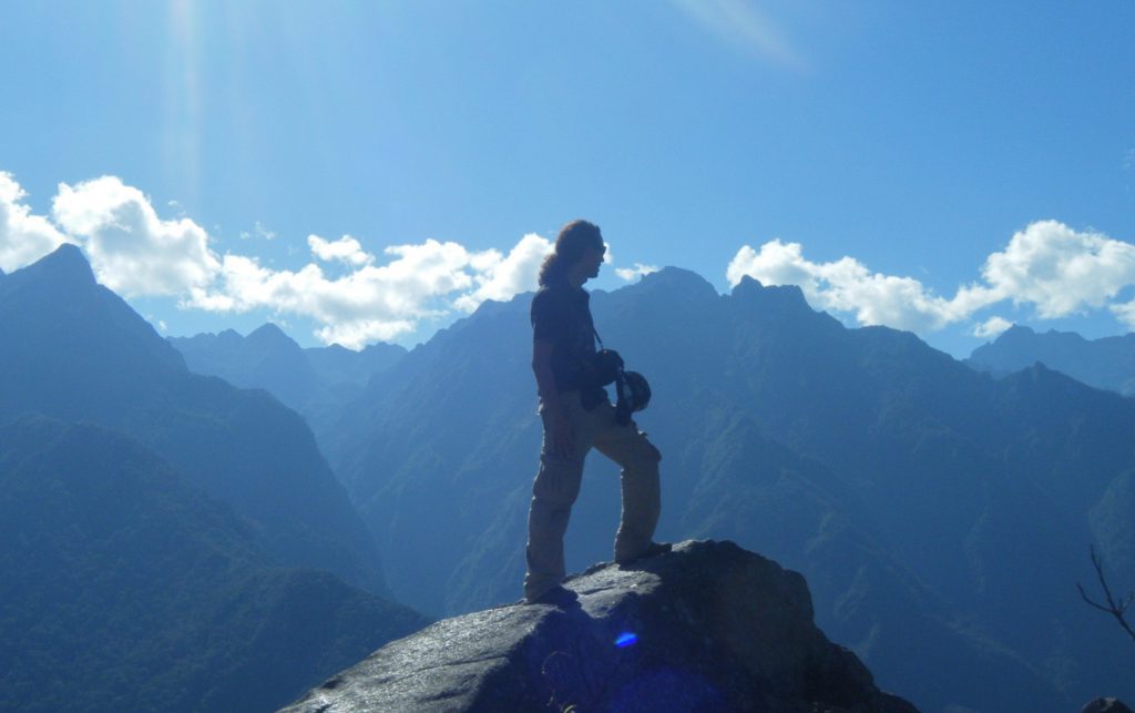 Inca Jungle Trail - Trekker on rock takes in cloud and mountain scenery.