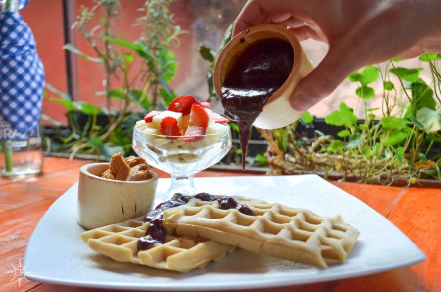 Vegetarian food in Peru - Hand pouring chocolate sauce onto waffles.