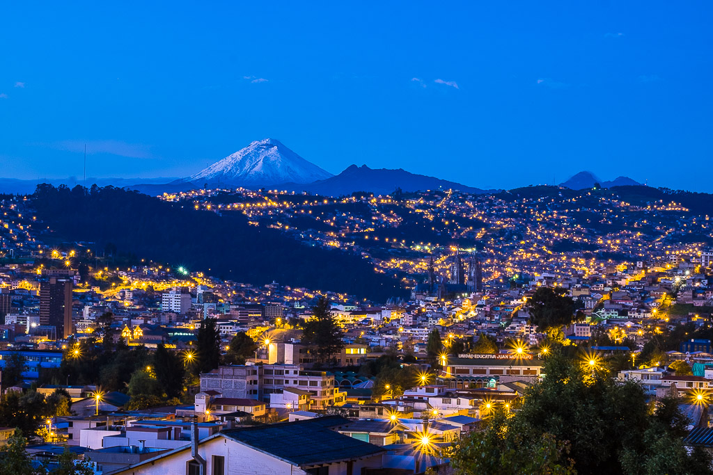 Snow-capped Cotopaxi Volcano with Quito city lights in foreground.