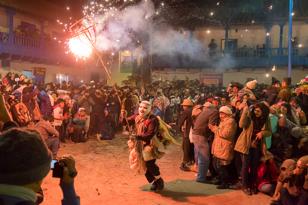 A masked character runs through the Virgin del Carmen Festival bearing fireworks