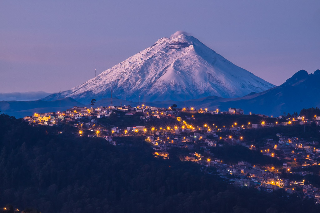 Snow-capped Cotopaxi volcano surrounded by the city lights of Quito.