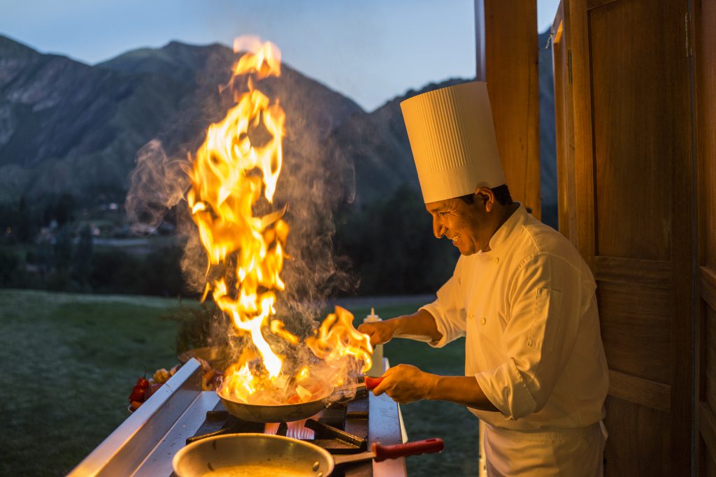 Luxury hotels in Sacred Valley - Chef with flaming pan during cooking classes at Inkaterra Hacienda.